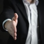 Close-up of a businessman extending hand for a handshake, symbolizing agreement and partnership.