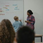 A teacher engages students in an interactive English lesson using a whiteboard and magnetic letters.