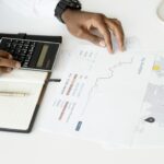 Overhead view of a person analyzing financial documents using a calculator for investment planning.
